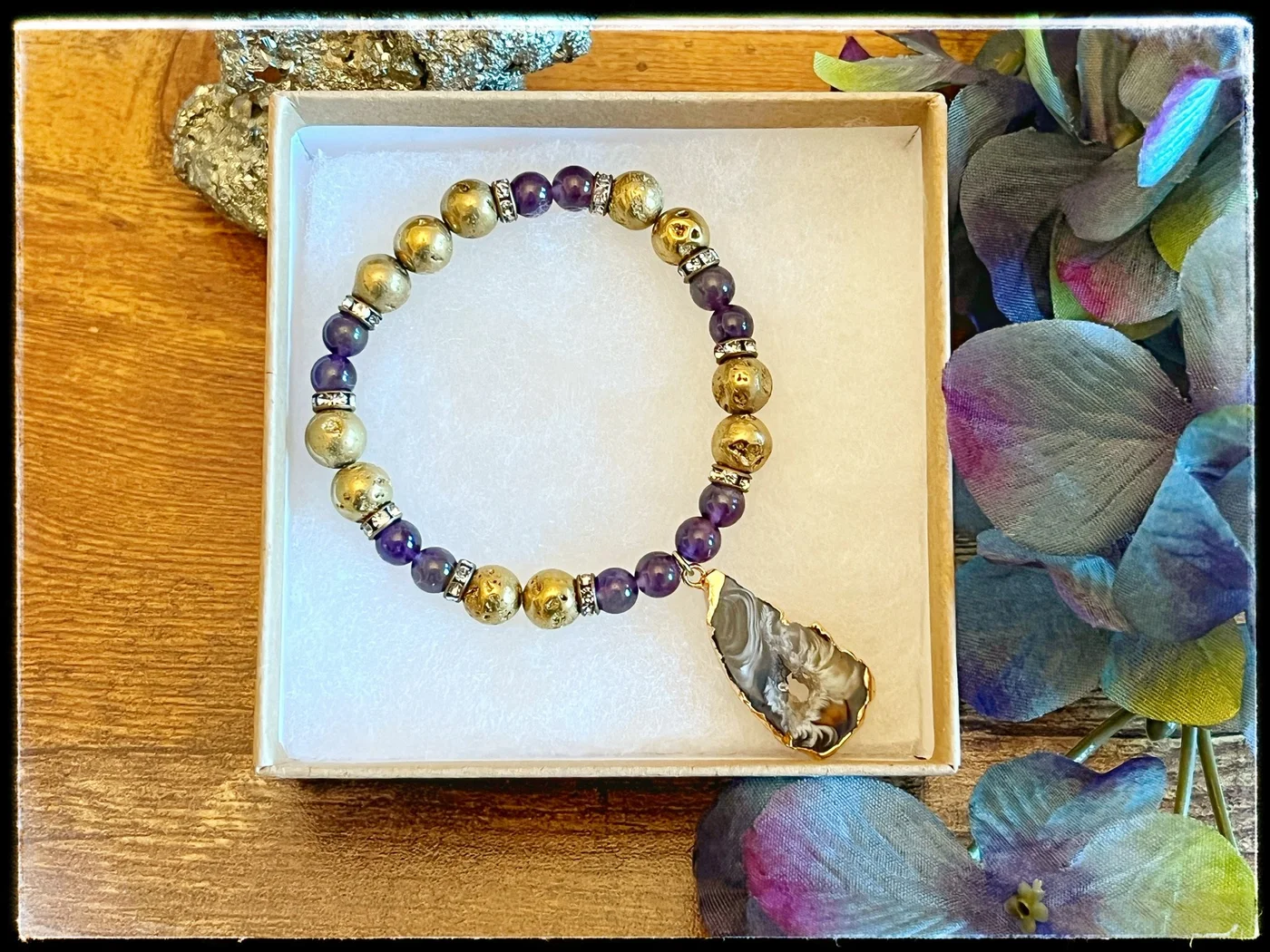 Gold and purple beaded bracelet with a large decorative pendant