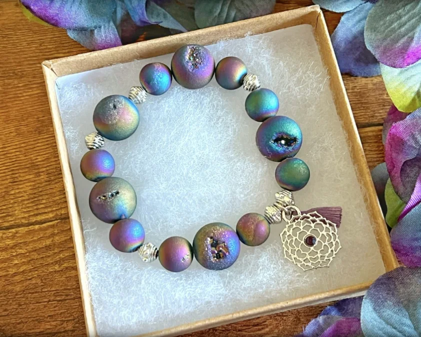 Purple and teal beaded bracelet with a round silver-tone charm in a gift box