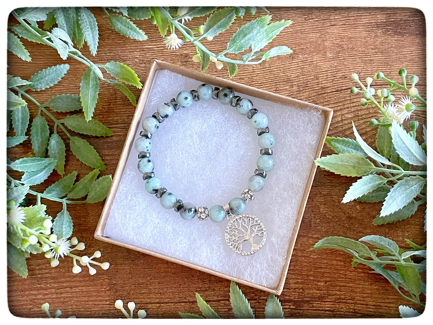 A lavender charm bracelet, photographed with greenery and flowers