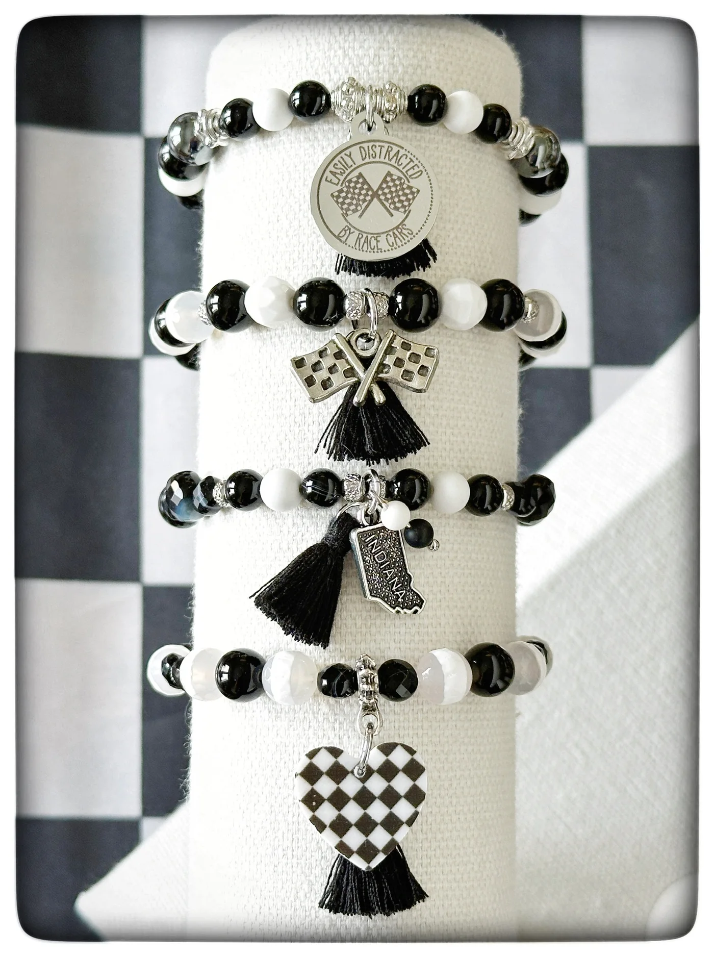 Black and white track day bracelets with themed charms on a display stand